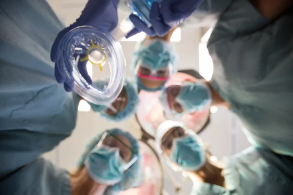 Médicos multiétnicos con máscara de oxígeno en la sala de operaciones —  Fotos de Stock