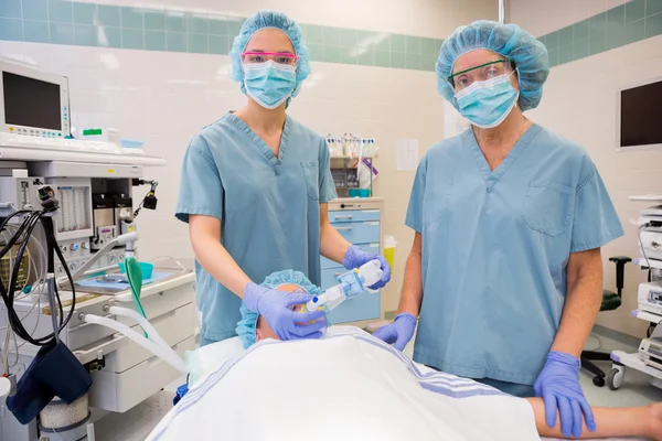 Enfermeras ajustando máscara de oxígeno en paciente femenino —  Fotos de Stock