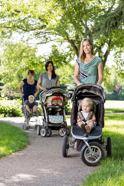 Mothers Pushing Baby Strollers In Park — Stock Photo, Image