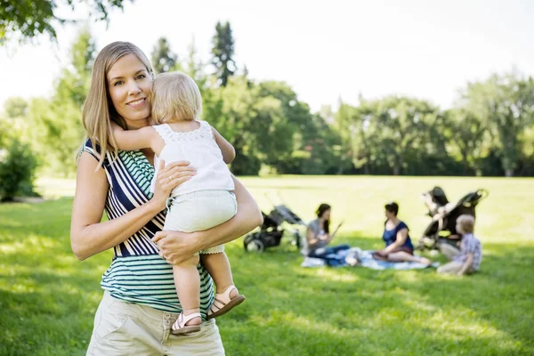 Mãe feliz carregando filha no parque — Fotografia de Stock