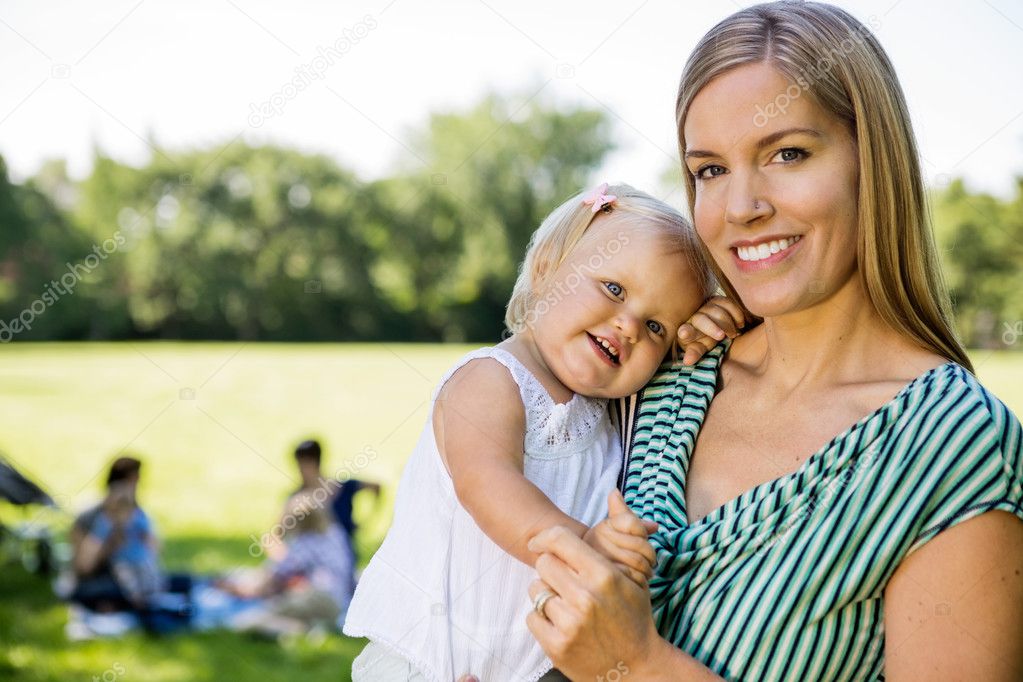 Happy Mother Carrying Cute Daughter In Park