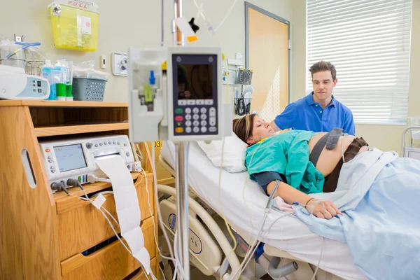 Άνθρωπος εξετάζοντας έγκυος γυναίκα ξαπλωμένος στο κρεβάτι του στο νοσοκομείο — Φωτογραφία Αρχείου