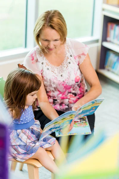 Lärare med skolflicka läser bok — Stockfoto