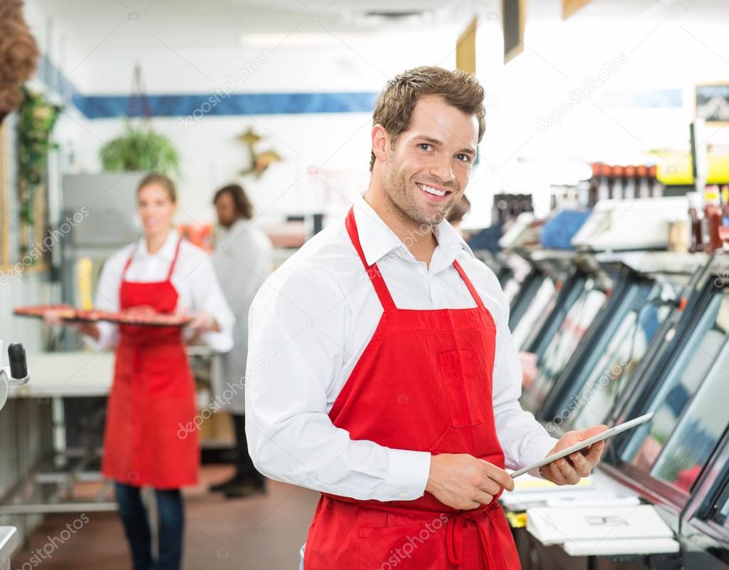 Portrait Of Happy Butcher Holding Digital Tablet At Store