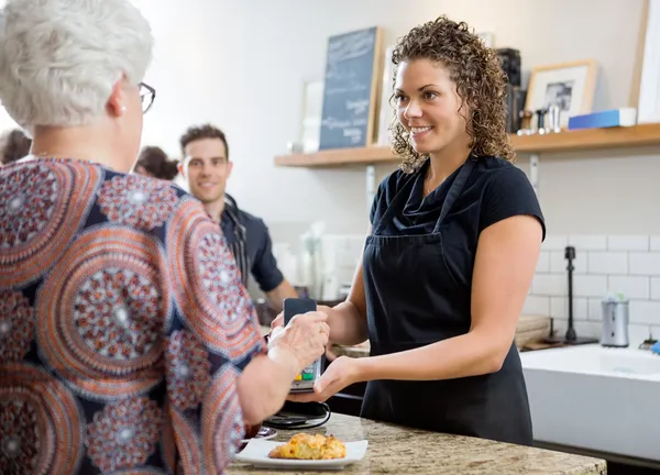 Kvinnan betalar genom smartphone på café — Stockfoto