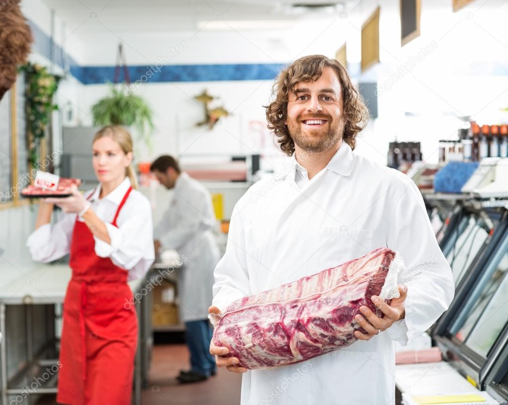Portrait Of Happy Butcher Holding Meat Package