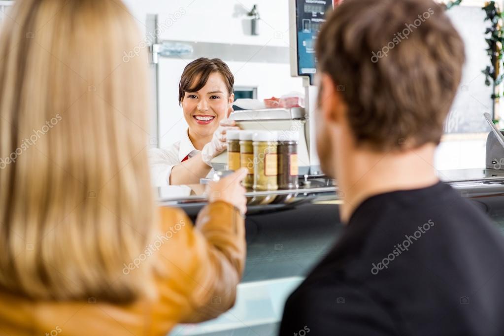 Saleswoman Attending Customers At Butcher's Shop