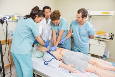 Medical Team Performing CPR On Dummy Patient clipart