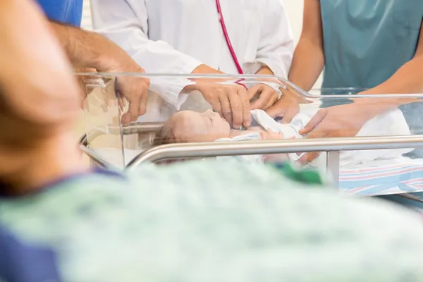 Médico examinando bebé mientras está de pie por la enfermera —  Fotos de Stock