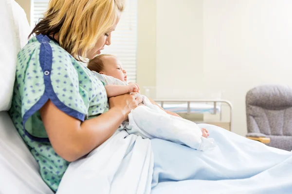Frau schaut neugeborenes Baby auf Krankenhausbett an — Stockfoto