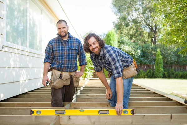 Felice lavoratori edili con livello di spirito in loco — Foto Stock