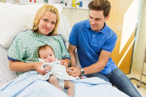 Vrouw met pasgeboren babymeisje zit door de mens in het ziekenhuis — Stockfoto