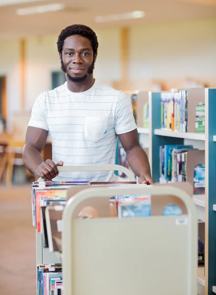 Bibliothecaris met Trolley van boeken In bibliotheek — Stockfoto