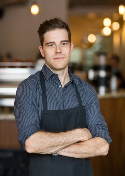 Jonge eigenaar staande wapens gekruist in café — Stockfoto