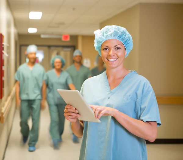 Medico con tavoletta digitale mentre il team cammina in ospedale Corrid — Foto Stock
