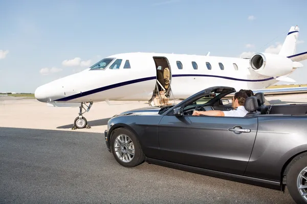 Pilot In Convertible Parked Against Private Jet — Stock Photo, Image