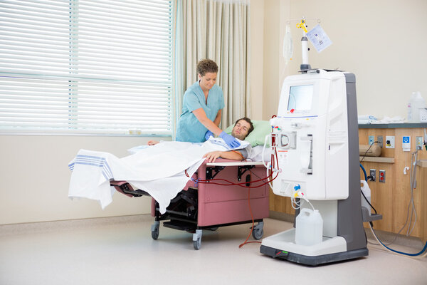 Nurse Covering Patient Receiving Renal Dialysis With Blanket