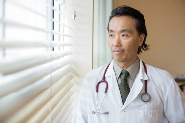 Médico reflexivo mirando por la ventana — Foto de Stock