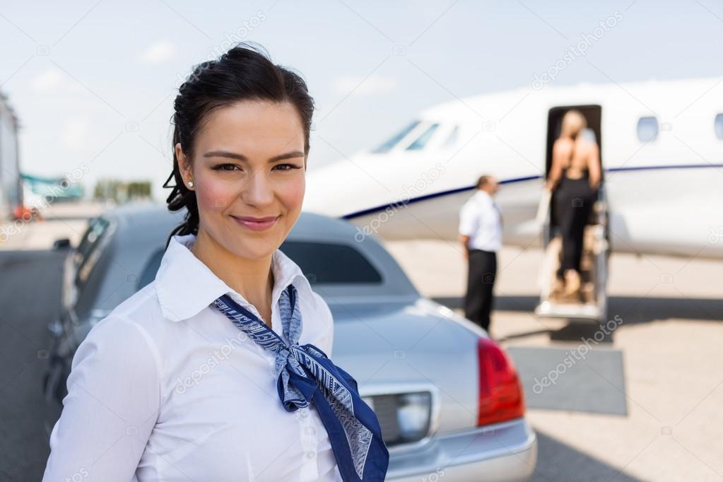 Beautiful Airhostess Standing Against Limousine And Private Jet