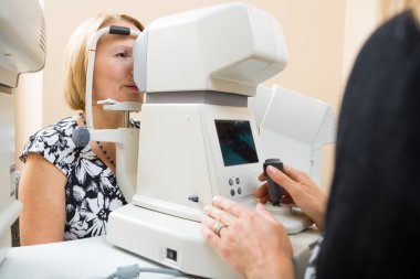 Optician Examining Patient's Eye With Tonometer clipart