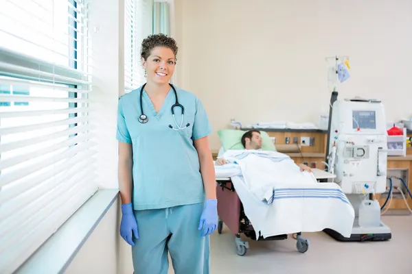 Sjuksköterska med patientens mottagande renal dialys i bakgrunden — Stockfoto