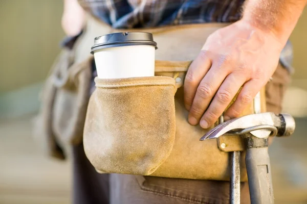 Disponibel kaffekopp och hammare på snickarens verktyg bälte — Stockfoto