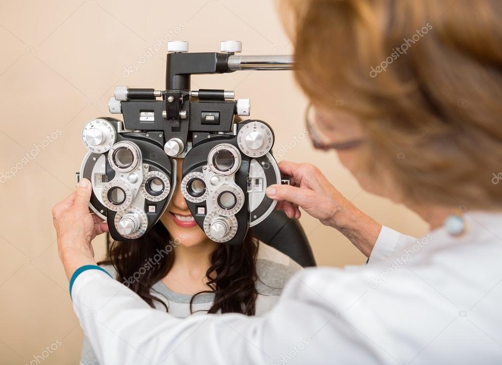 Optometrist Adjusting Phoropter For Patient