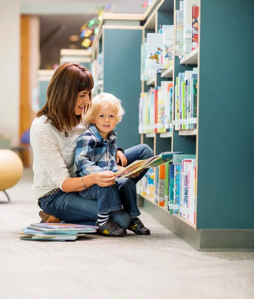 Studente con insegnante lettura libro in biblioteca — Foto Stock