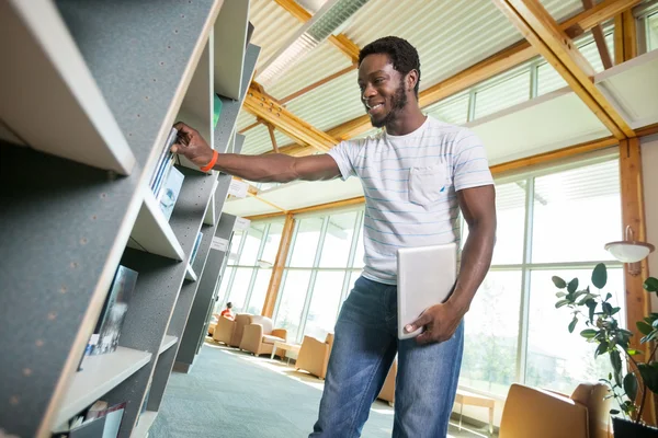 Student selecteren boek in bibliotheek — Stockfoto