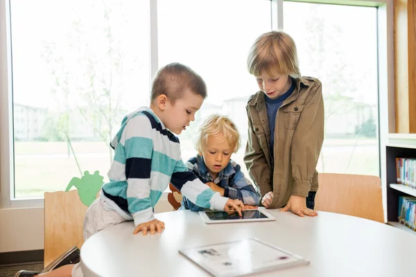Meninos usando tablet digital na biblioteca — Fotografia de Stock
