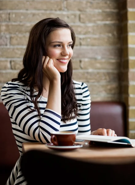 Femme avec la main sur le menton regardant loin dans la cafétéria — Photo