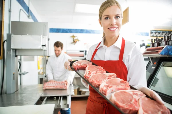 Buon macellaio mostrando vassoio di carne in negozio — Foto Stock