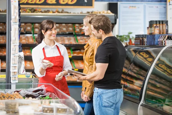 Verkäuferin hilft Paar beim Fleischkauf — Stockfoto