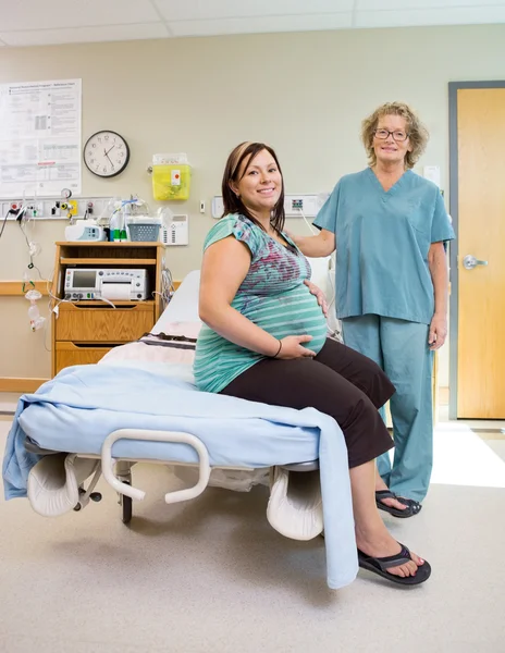 Glad sjuksköterska med gravid kvinna i sjukhussal — Stockfoto