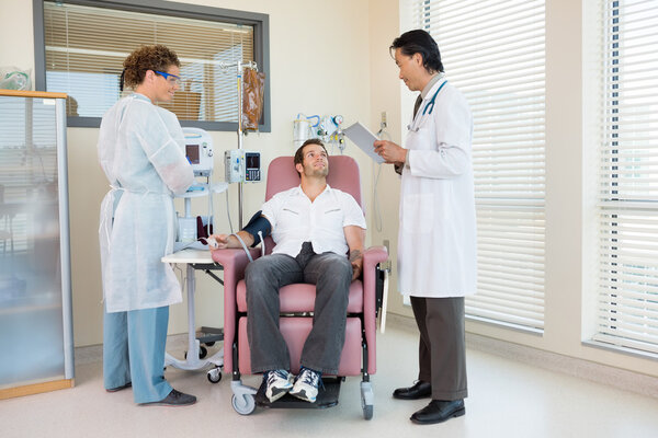 Patient Looking At Doctor Holding Digital Tablet In Hospital Roo