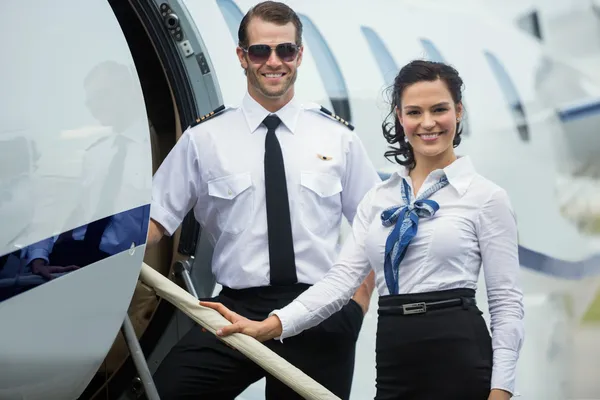 Happy Airhostess And Pilot Standing On Private Jet 's Ladder — стоковое фото