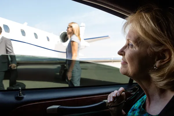 Mujer de negocios en coche mirando jet privado —  Fotos de Stock