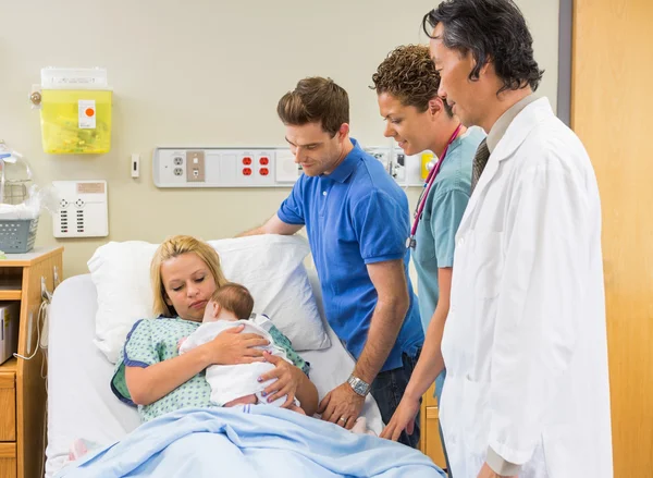 Медичні команди і чоловік дивиться на матір з babygirl — стокове фото
