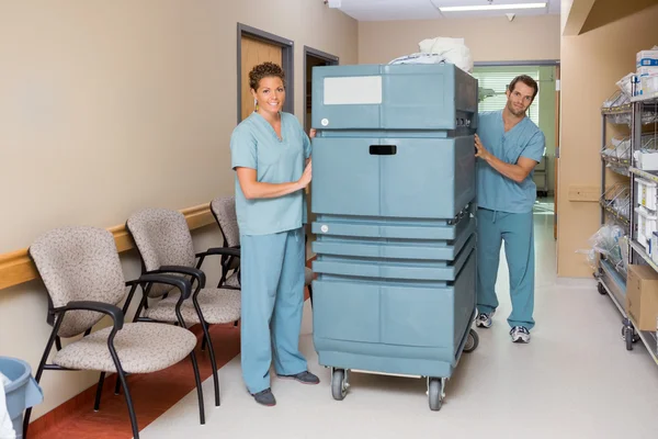 Verpleegkundigen duwen trolley koffer in ziekenhuis gang — Stockfoto