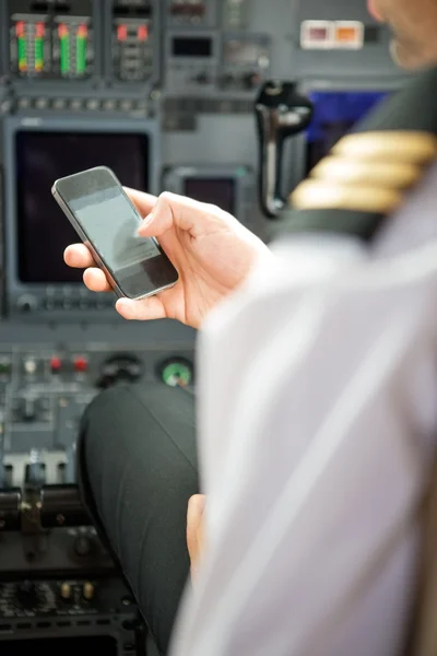 Piloten gebruikend smartphone in cockpit — Stockfoto