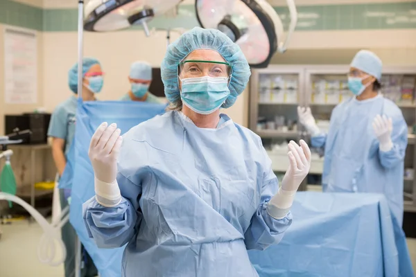 Doctor en vestido quirúrgico con el equipo en la sala de operaciones — Foto de Stock