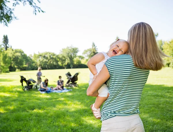Mãe carregando alegre filha no parque — Fotografia de Stock