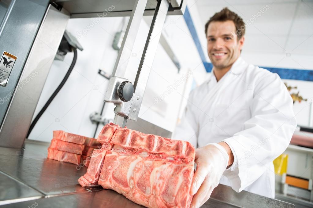 Male Butcher Cutting Meat On Bandsaw