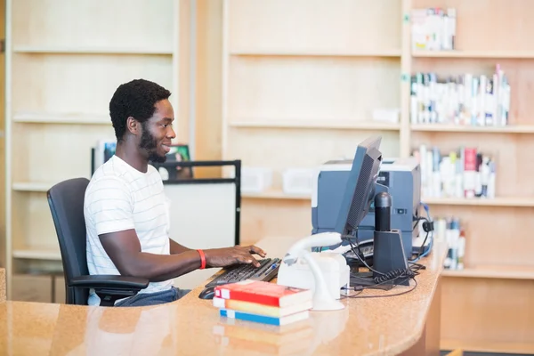 Bibliotekarie arbetar på stationär dator i biblioteket — Stockfoto