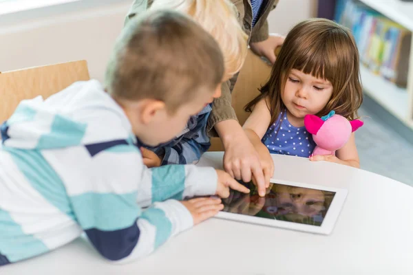 Дети, использующие цифровой планшет в школьной библиотеке — стоковое фото