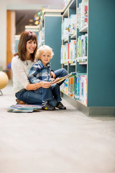 Glücklicher Lehrer und Junge lesen Buch in der Bibliothek — Stockfoto