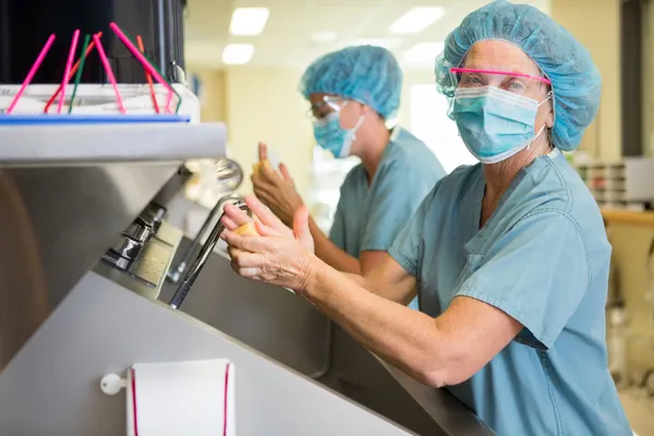 Läkare skrubba händer med kollega — Stockfoto