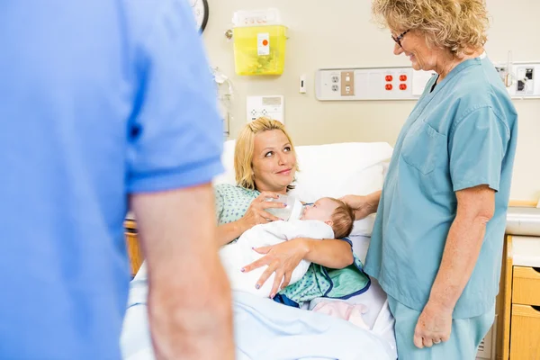 Mulher olhando para enfermeira enquanto alimenta leite para a babygirl — Fotografia de Stock