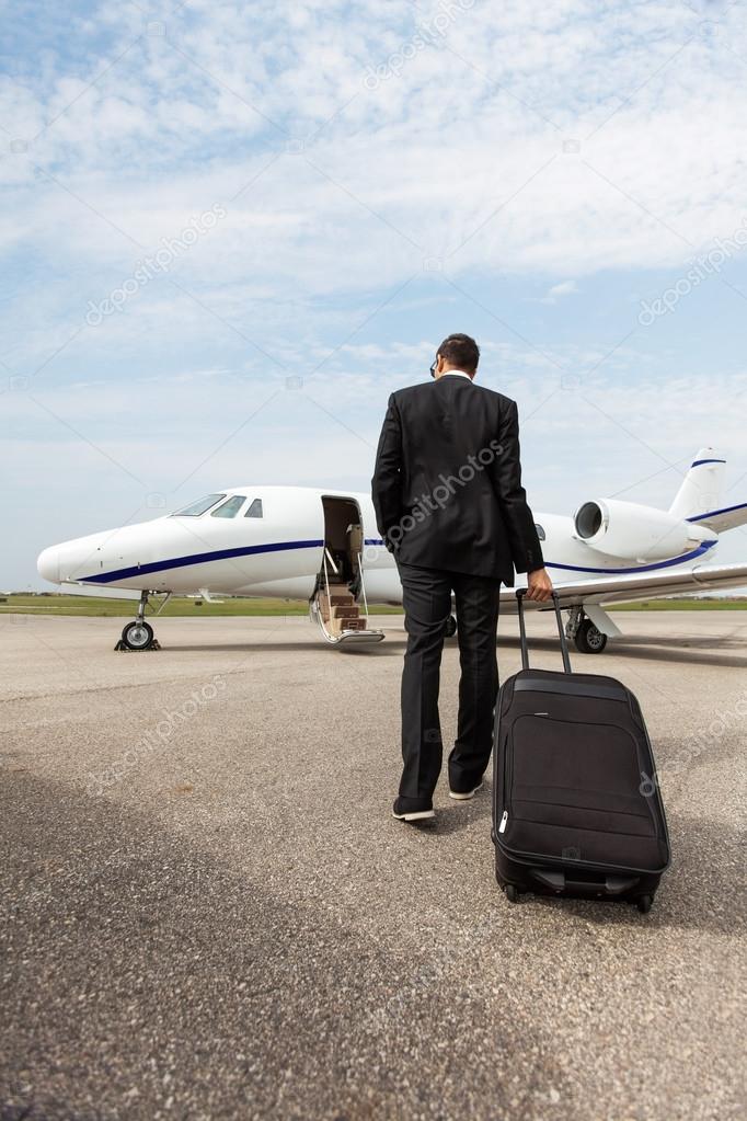 Businessman With Luggage Walking Towards Private Jet