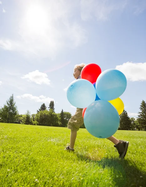 Junge mit Heliumballons läuft in Park — Stockfoto